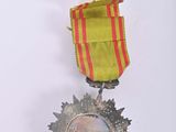 a silver medal with a red and yellow ribbon on it