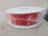 a spool of red filamant wrapped in plastic
