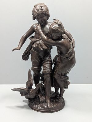 statue représentant trois enfants jouant avec un oiseau, posée sur un socle