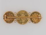 a close up of a gold plated brooch with two coins on it