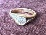 une bague en or sertie d'un diamant, posée sur un fond violet