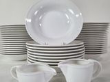 a stack of white dishes and cups on a table
