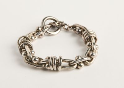 gros plan d'un bracelet en argent sur une surface blanche