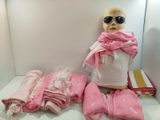 un mannequin portant une écharpe rose et des lunettes de soleil, à côté d'une pile de serviettes pliées