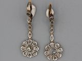 two pairs of earrings with diamonds on them on a gray surface