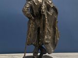 a bronze statue of a man with a hat and a cane
