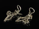 a pair of silver earrings on a black surface