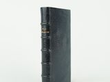 un vieux livre noir surmonté d'une reliure dorée