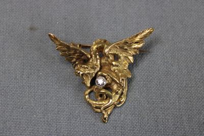 une image représentant une broche plaquée or sur laquelle figure un oiseau sur la tête