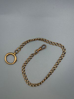 a close up of a gold chain with a ring on it