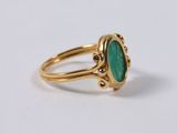 a close up of a gold ring with a green stone