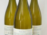 trois bouteilles de vin blanc sont alignées sur une surface blanche