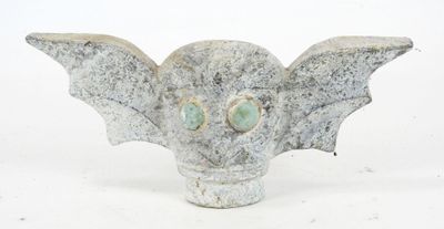 une petite statue représentant une chauve-souris aux yeux verts