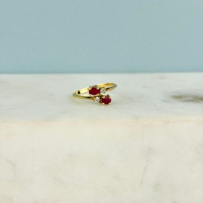 a close up of a gold ring with two red stones on a marble surface
