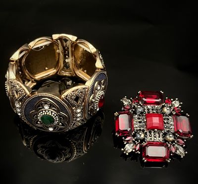 une paire de bracelets rouges et verts et une bague posés sur un fond noir