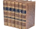 four old books sitting on top of each other on a white surface