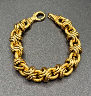 a close up of a gold chain bracelet on a table