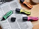 four different colored pens sitting on top of a newspaper