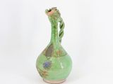 un vieux vase vert posé sur une table blanche