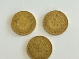 three gold coins sitting on top of a white surface