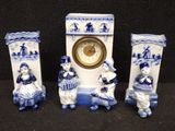 three blue and white figurines are sitting next to a clock