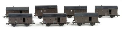 six miniature train cars are lined up in a row on a white surface