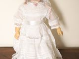 une poupée qui porte une robe blanche et un chapeau