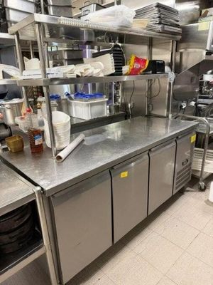 un plan de travail en acier inoxydable dans une cuisine professionnelle, sur lequel sont posés de nombreux plats