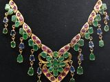 un collier en or orné de pierres vertes, violettes et bleues