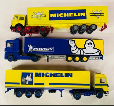 trois camions miniatures alignés sur une surface blanche