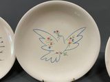 three plates with a bird painted on them on a table