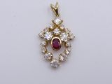 a close up of a pendant with a ruby and white topaz