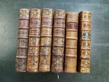 six vieux livres alignés en rang sur une table