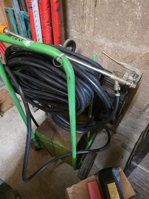 une brouette à laquelle est fixé un tuyau d'arrosage, dans un garage
