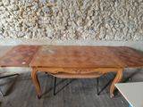 une table en bois sur laquelle sont posées deux rallonges, devant un mur en pierre