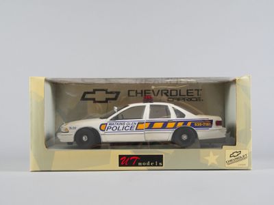 Une voiture de police Chevrolet dans une boîte, posée sur une surface blanche