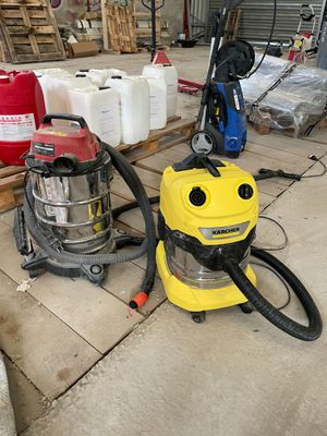 un aspirateur jaune et noir et un bidon rouge et blanc posés par terre