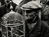black and white photo of a man holding a bird in a cage