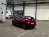 a red car parked in a parking lot in front of a building