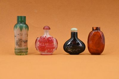 quatre bouteilles en verre de couleurs différentes posées les unes à côté des autres sur une surface marron