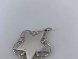 a close up of a silver star pendant on a white surface