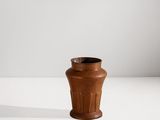 un petit vase brun posé sur une surface blanche