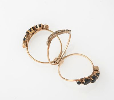two gold rings with black stones on them on a white surface
