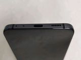 the back of a black cell phone sitting on top of a white table
