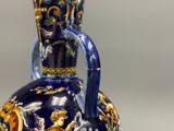un vase bleu et jaune muni d'une anse, posé sur une table