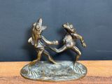 bronze figurine of two frogs fighting with each other on a table
