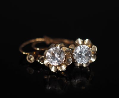 une paire de boucles d'oreilles en or et diamants sur une surface noire