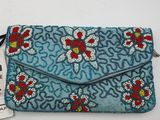 a blue clutch bag with red and white flowers on it