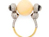 a close up of a ring with a pearl and diamonds on it