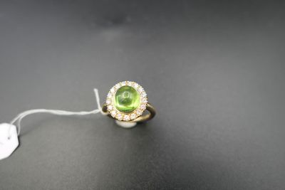 gros plan d'une bague avec une pierre verte entourée de diamants blancs